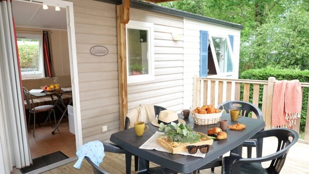 Eine überdachte Terrasse mit einem für das Frühstück gedeckten Tisch, darunter Croissants und Kaffee.
