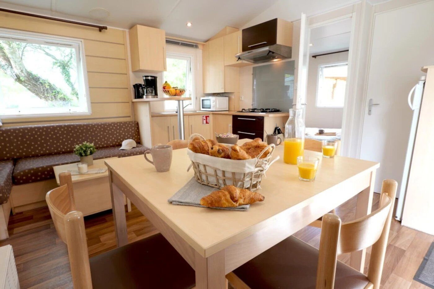 A cozy kitchen with a dining table set for breakfast, featuring croissants and orange juice.