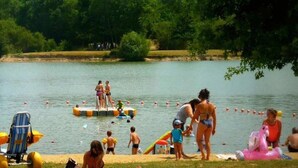 Een meerlandschap met mensen die zwemmen en zonnebaden.