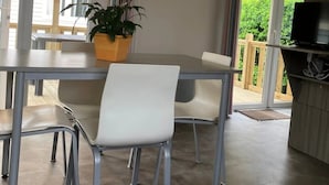 Een moderne eethoek met een tafel, stoelen, een potplant en een televisie op een standaard.