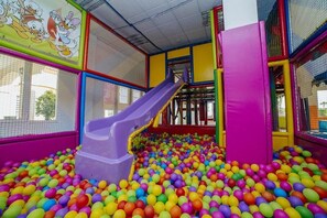 A play area with a slide and a ball pit filled with multicolored balls.