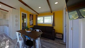 A compact living space with a dining area, a sofa, and a kitchen. - ZEcamping 5* familial espace aquatique locatif TV LV clim 32m2 5 pers (Sant Felip Neri)