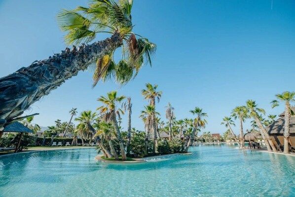A swimming pool with palm trees and a tropical setting.