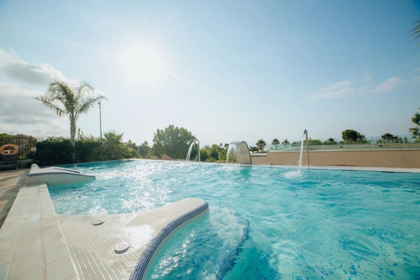 A swimming pool with a tiled deck, a lounge chair, and a lifebuoy.