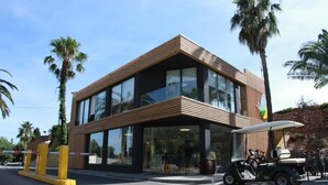 Un edificio moderno con estructura de dos pisos, grandes ventanales y fachada de madera.