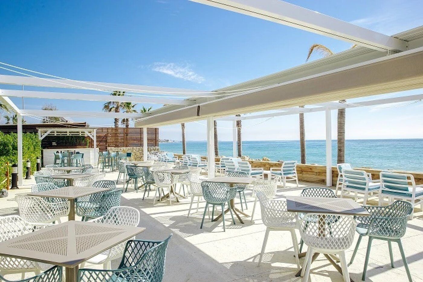 Un patio al aire libre con mesas y sillas, con vista al mar.