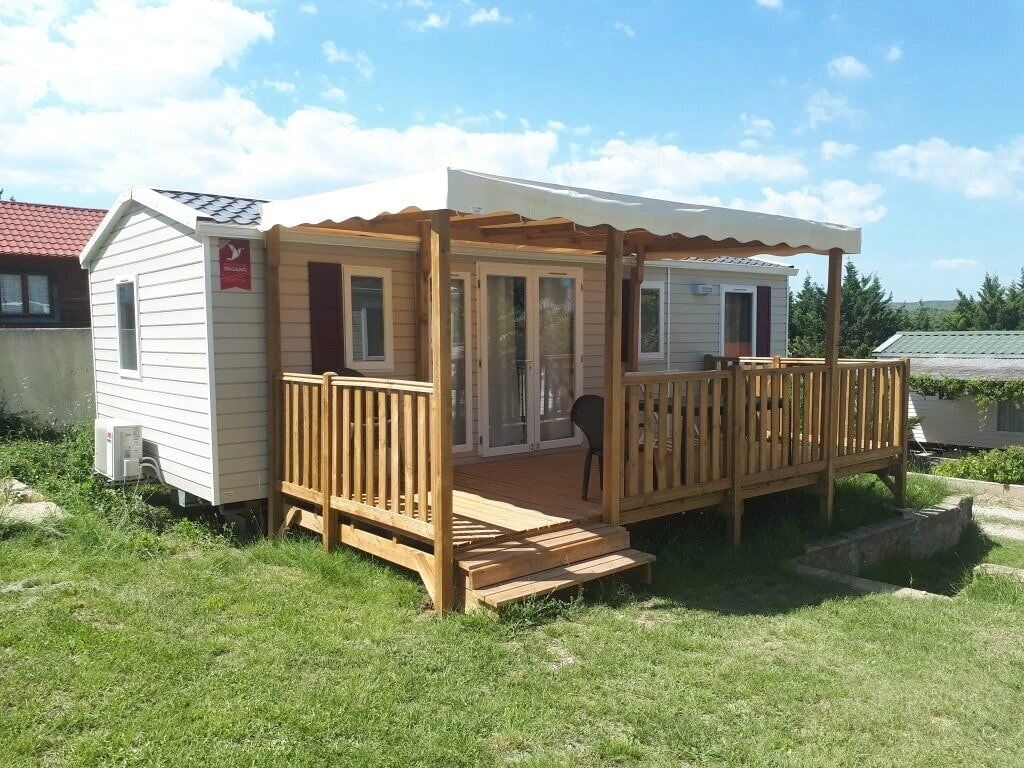 A mobile home with a wooden deck and a covered porch.