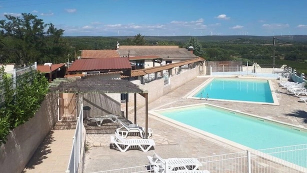 A pool area with lounge chairs and a view of the surrounding landscape. - ZEcamping 3 étoiles pataugeoire piscine mobil-home TV clim 25m2 4 pers (Montagnac)