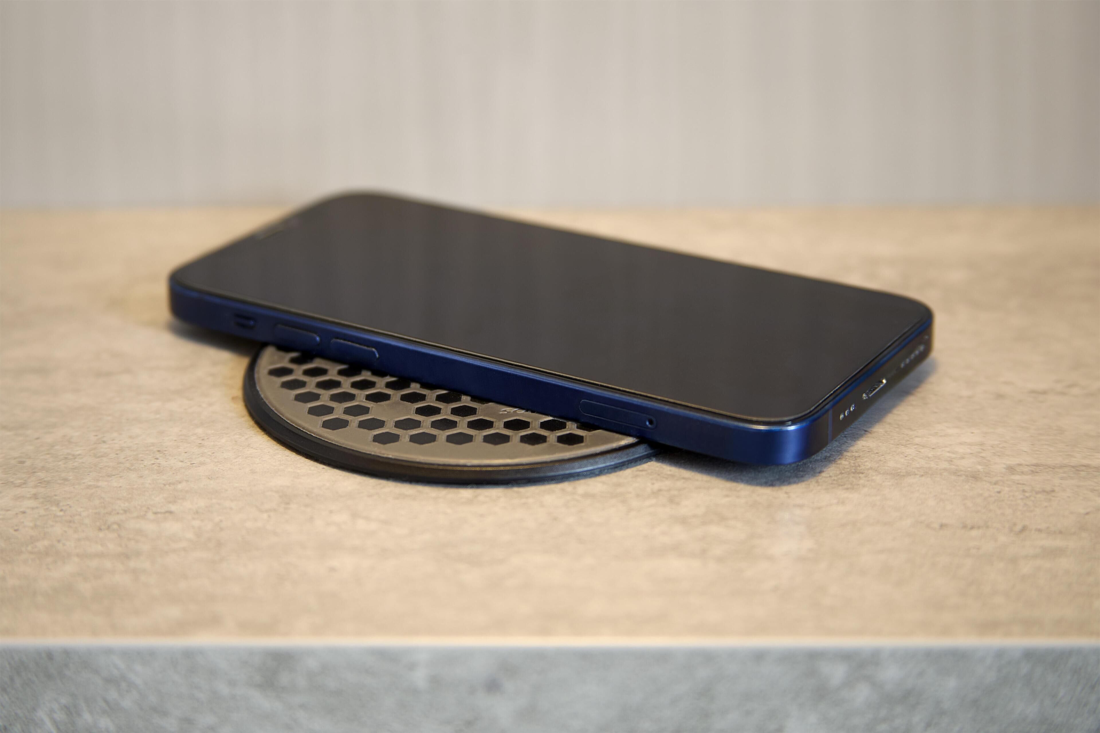 A smartphone on a textured surface with a circular object beside it.