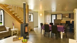 Een moderne woonkamer met een open haard, een eethoek en een keuken.