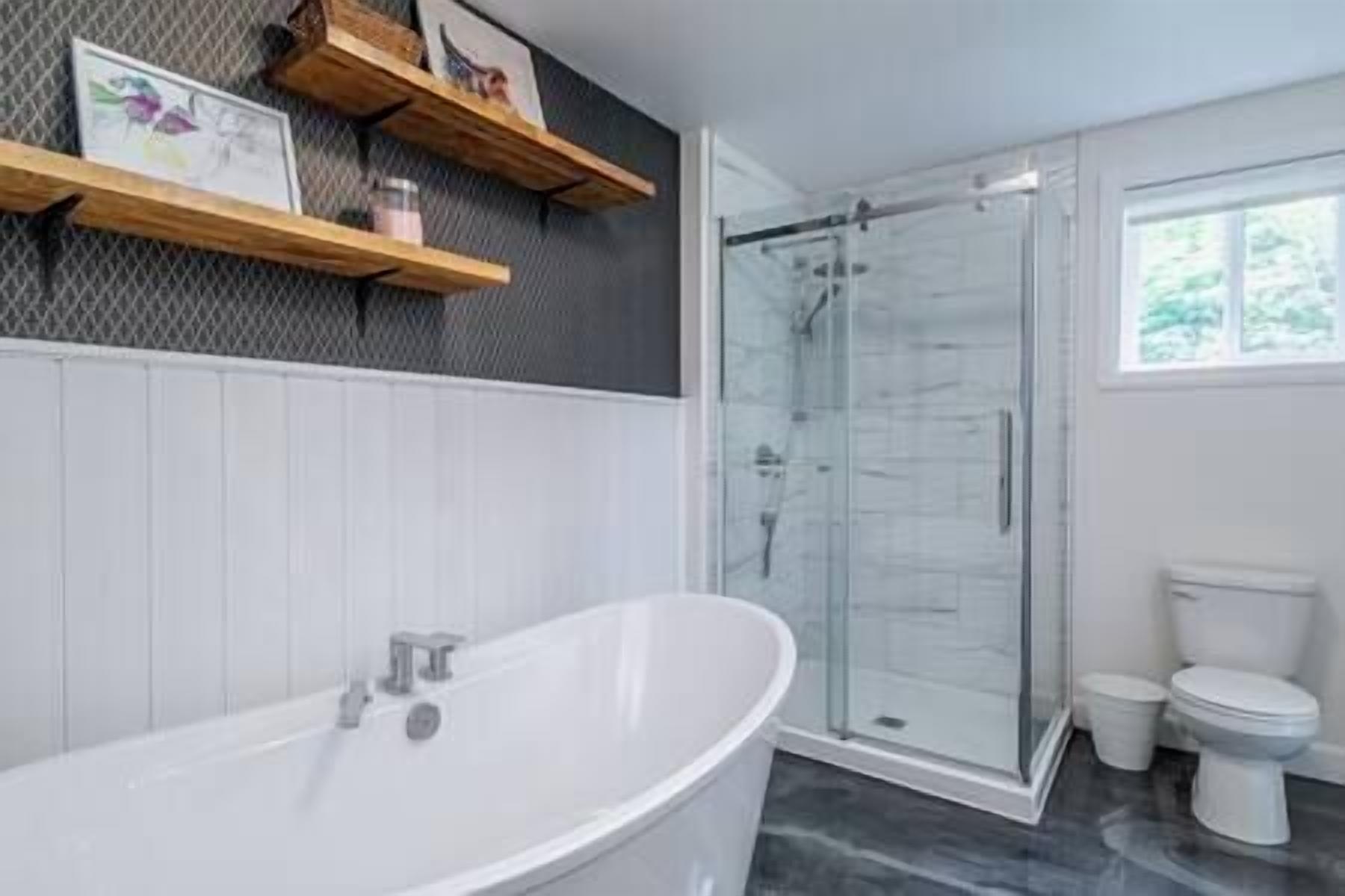 A modern bathroom with a freestanding bathtub, a glass-enclosed shower, and a toilet.