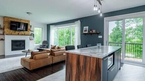 Una cocina moderna con una isla central, horno empotrado y zona de comedor con sofá.