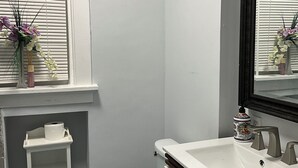 Une salle de bain avec des toilettes, un lavabo et une fenêtre équipée de stores.