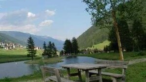A picnic table by a lake with mountains in the background. - ZEcamping 2* animations locatif TV 40m2 5 pers (Fucine)