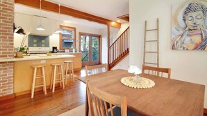 A dining area with a wooden table, bar stools, and a Buddha painting on the wall. - Downton Abbottry 2/2 - 5 Min Walk To City Gates (St. Augustine)