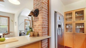 A kitchen with a brick column, wooden cabinets, a stainless steel refrigerator, and a white countertop. - Downton Abbottry 2/2 - 5 Min Walk To City Gates (St. Augustine)