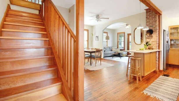 A wooden staircase leading to a living area with a kitchen, dining table, and a sofa. - Downton Abbottry 2/2 - 5 Min Walk To City Gates (St. Augustine)