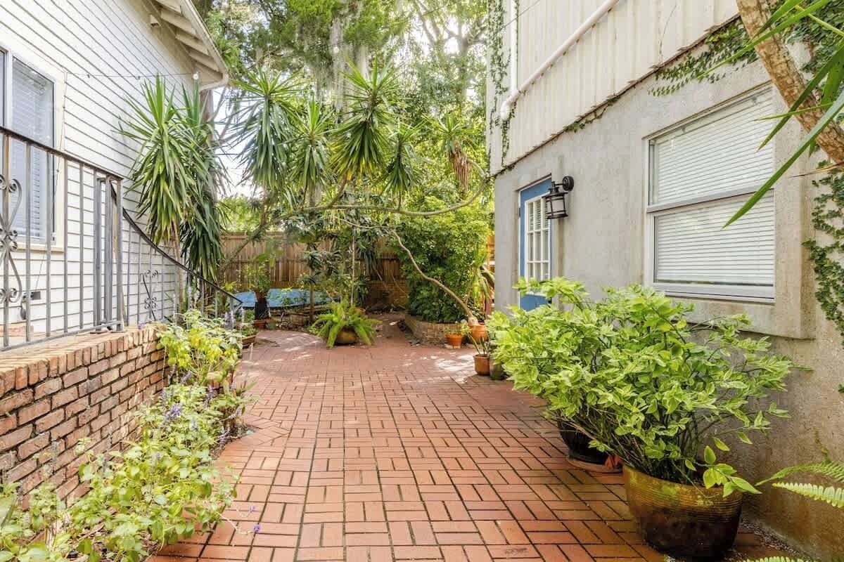 A brick-paved courtyard with potted plants and a wooden fence.