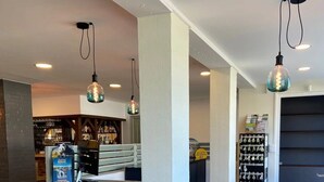 Zona de bar moderna con mostrador de ladrillo, iluminación colgante y una barra visible repleta de botellas.