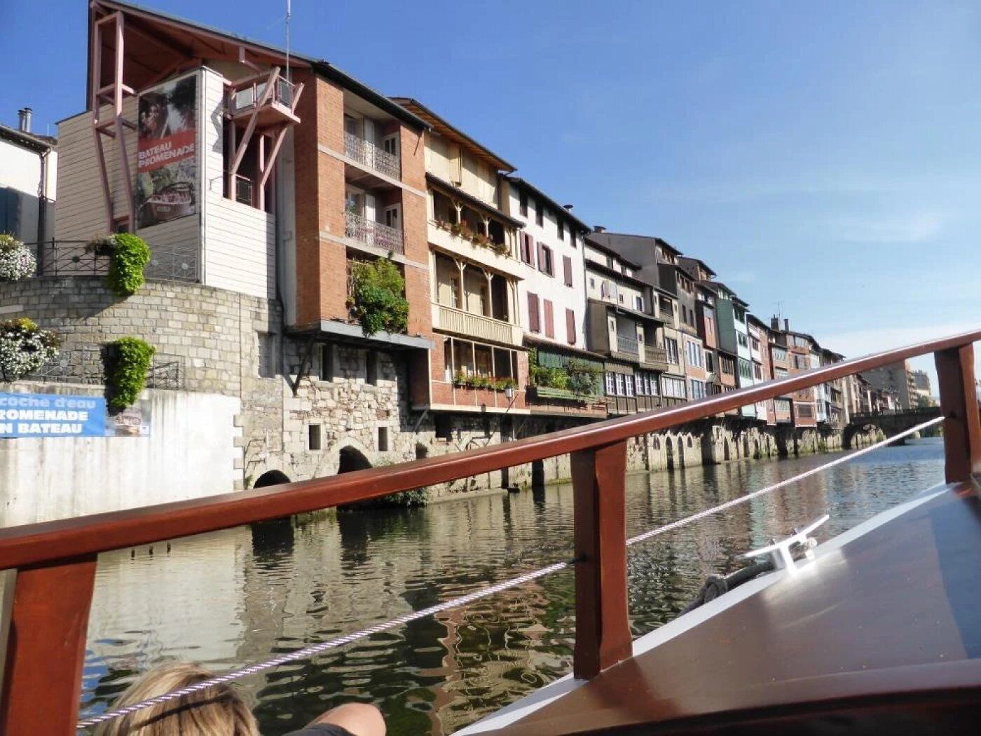 A riverside building with multiple balconies and a stone facade.