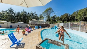 A pool area with clear blue water, lounge chairs, and umbrellas.