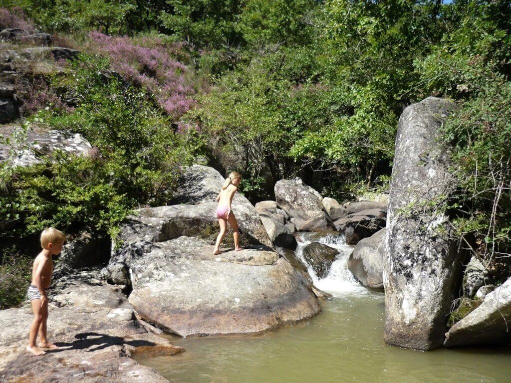 A natural outdoor setting with large rocks and a small stream.