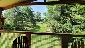 A covered outdoor area with a wooden deck and a view of a grassy path leading through a wooded area. - ZEcamping 3 étoiles pataugeoire piscine chiens acceptés locatif LV (Le Bez)