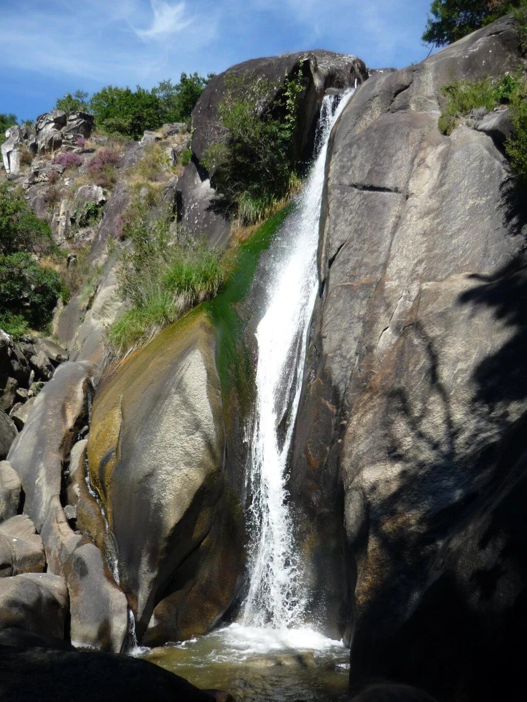 A waterfall cascading over large rocks in a natural setting.