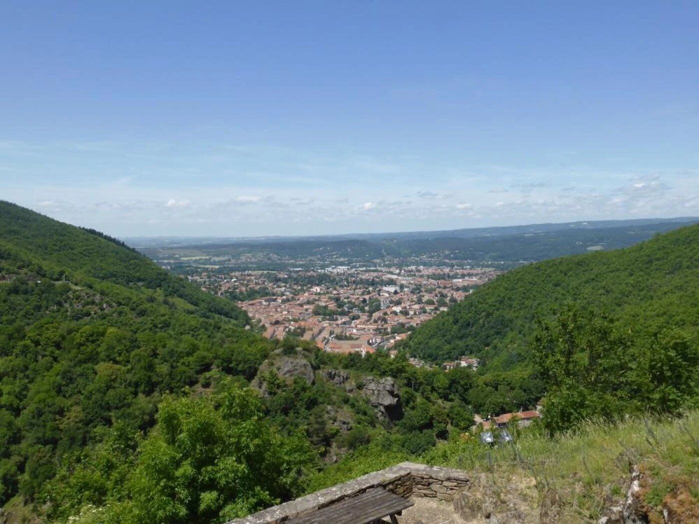 A panoramic view of a town nestled in a valley, surrounded by lush green hills.