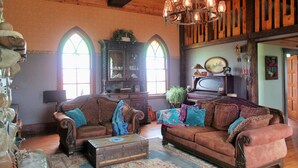 A cozy living room with a wooden ceiling, a vintage piano, and a chandelier. - Quaint lodge wonderful for retreats, reunions, weddings, and relaxation! (Glenwood)