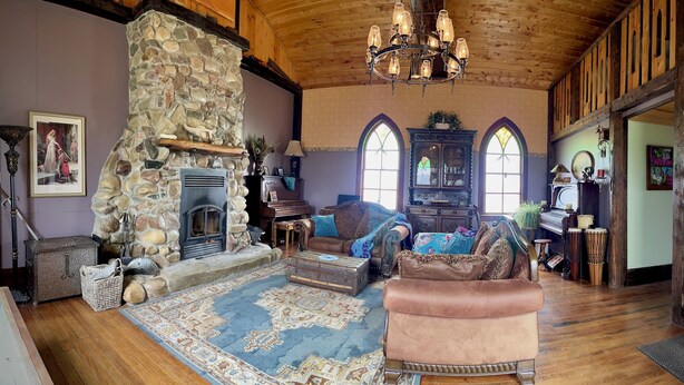 A cozy living room with a stone fireplace, leather furniture, and a large rug. - Quaint lodge wonderful for retreats, reunions, weddings, and relaxation! (Glenwood)
