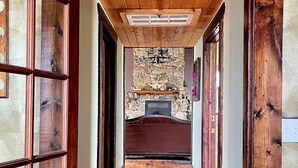 A wooden hallway with a stone fireplace, wooden doors, and a ceiling with a skylight. - Quaint lodge wonderful for retreats, reunions, weddings, and relaxation! (Glenwood)