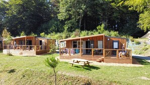 Two wooden cabins with balconies, a picnic table, and a small tree in the foreground. - ZEcamping 3 étoiles pataugeoire piscine dog friendly locatif LV 40m2 (Le Bez)