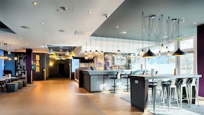 A modern bar area with a bar counter, high chairs, and pendant lighting.