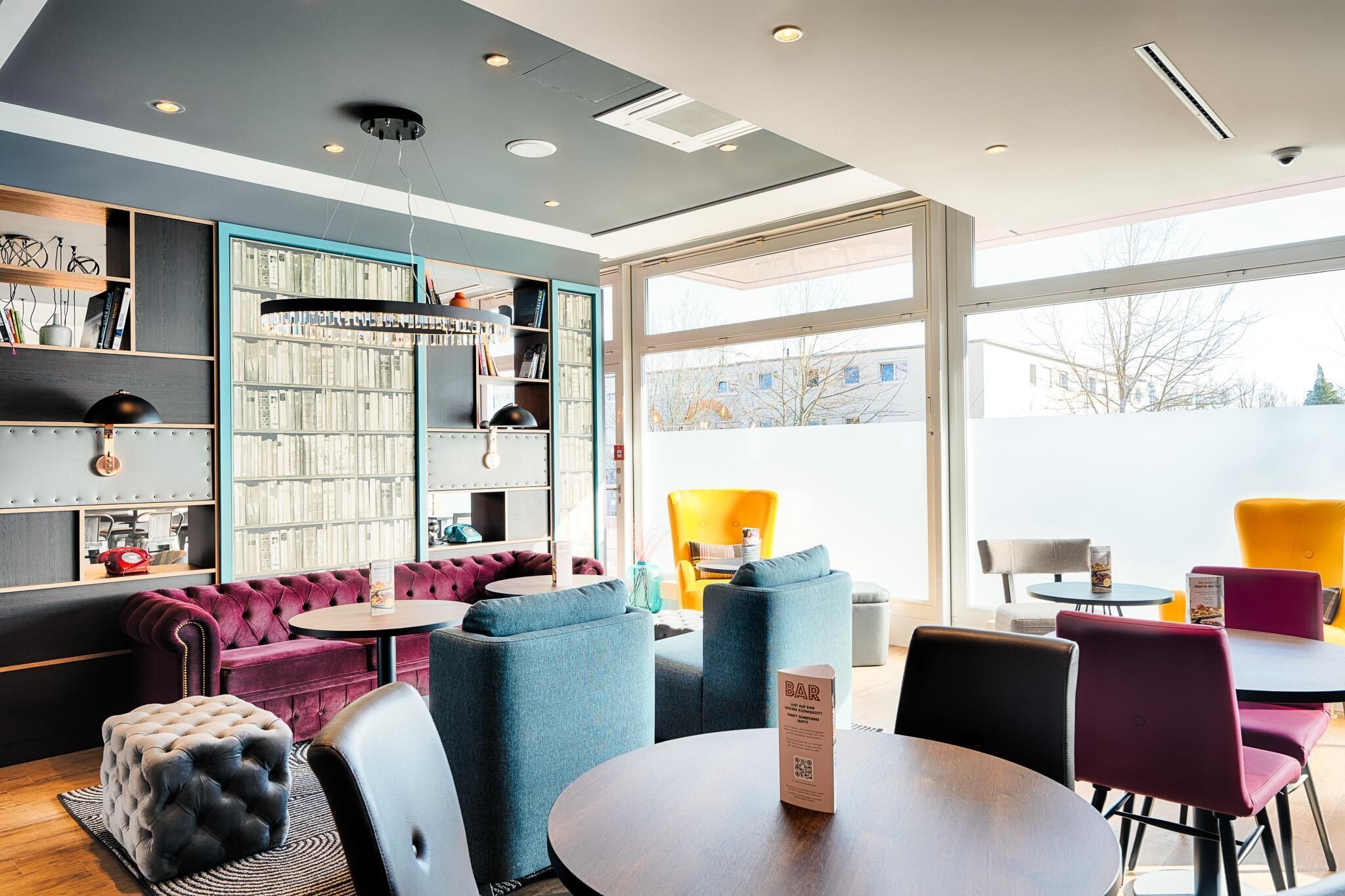 Et moderne loungeområde med siddepladser, en bar og et stort vindue med udsigt udad.