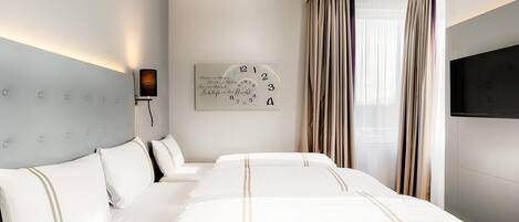 Una habitación de hotel con una cama grande, un televisor montado en la pared y un reloj.