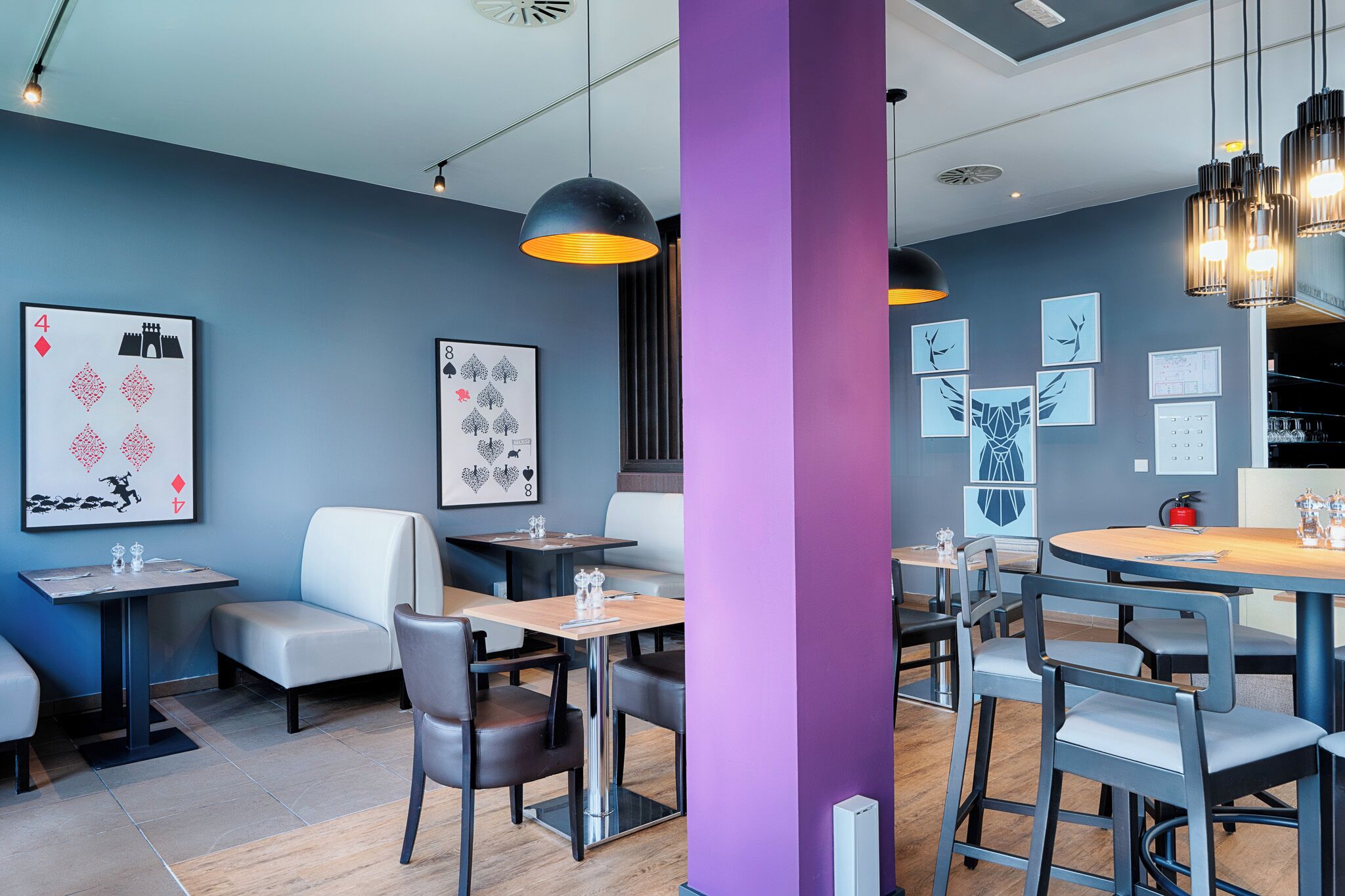 A modern restaurant interior with a blue wall, black and white decor, and a purple accent wall.