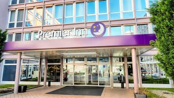A hotel entrance with a glass facade, a purple awning, and a logo with a crescent moon and stars.
