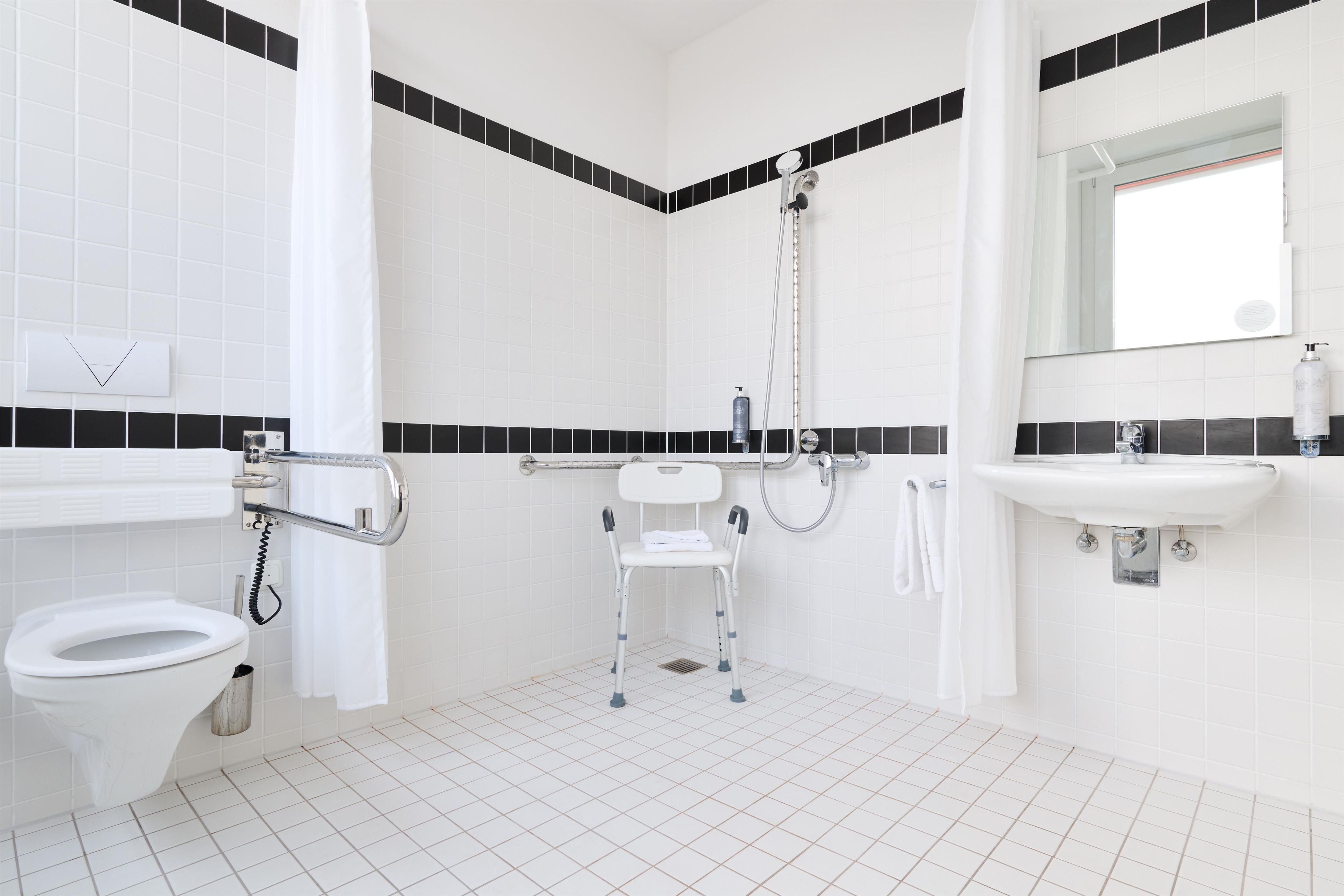 Une salle de bain équipée de toilettes, d’une douche, d’un lavabo et d’un miroir.