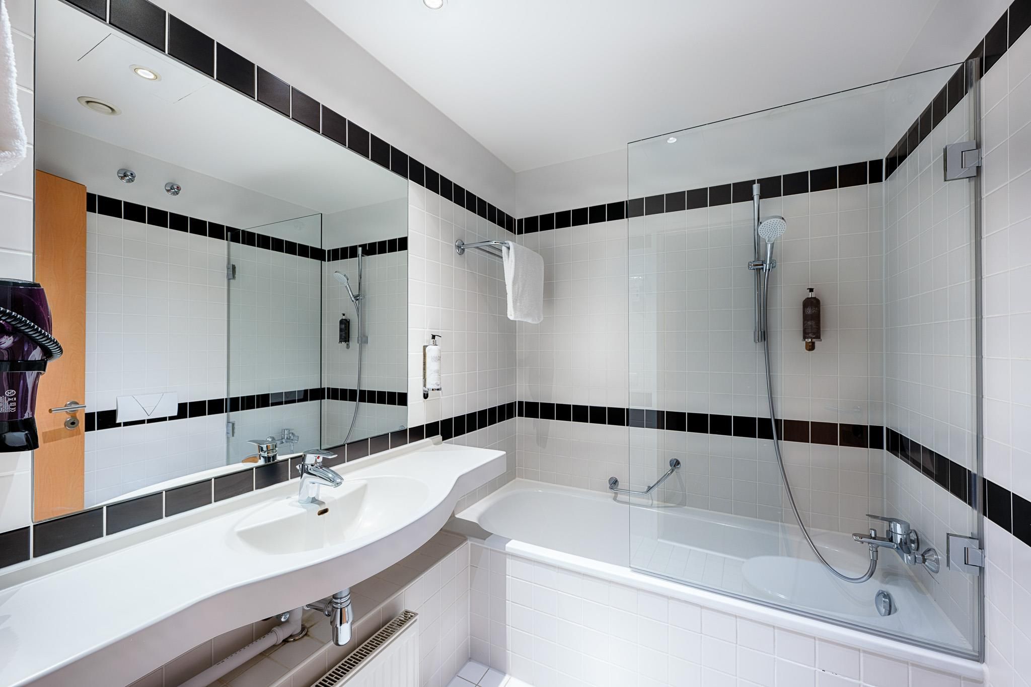 Un baño moderno con un lavamanos blanco, una bañera y una zona de ducha.