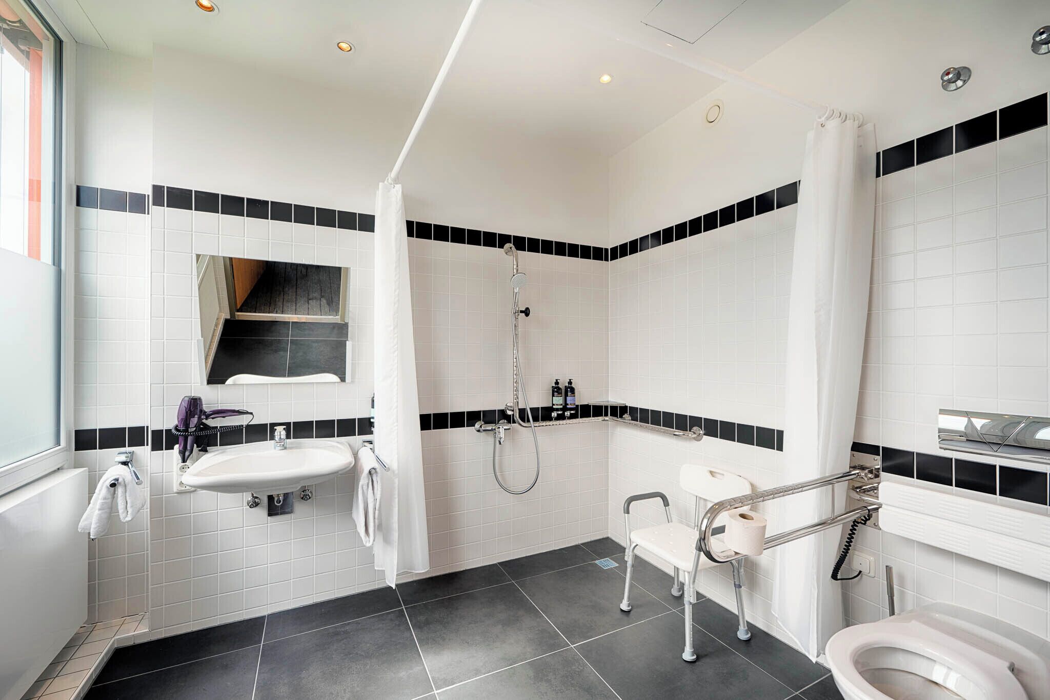 Un baño moderno con lavamanos blanco, inodoro y zona de ducha.