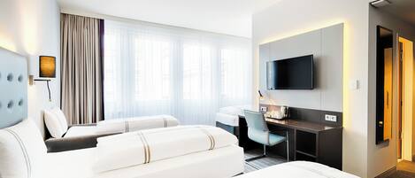 Habitación de hotel con dos camas, un escritorio, una silla, un televisor y un ventanal con cortinas.
