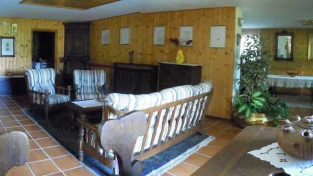 A traditional room with wooden paneling, a sofa, armchairs, a small table, and a cabinet.