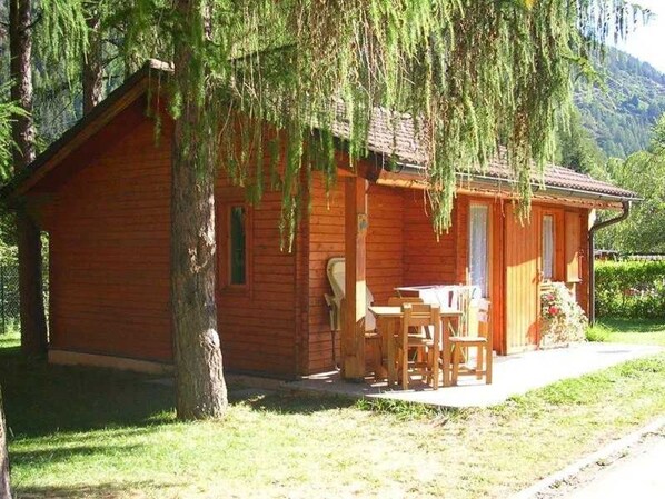 A wooden cabin with a porch and a table and chairs.