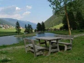A picnic table by a lake with mountains in the background.