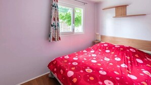 Un dormitorio con una cama, una ventana con cortinas y una estantería de madera en la pared.