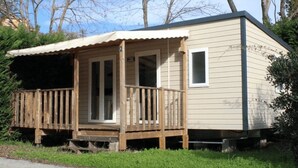A small, single-story cabin with a wooden deck and a covered porch.