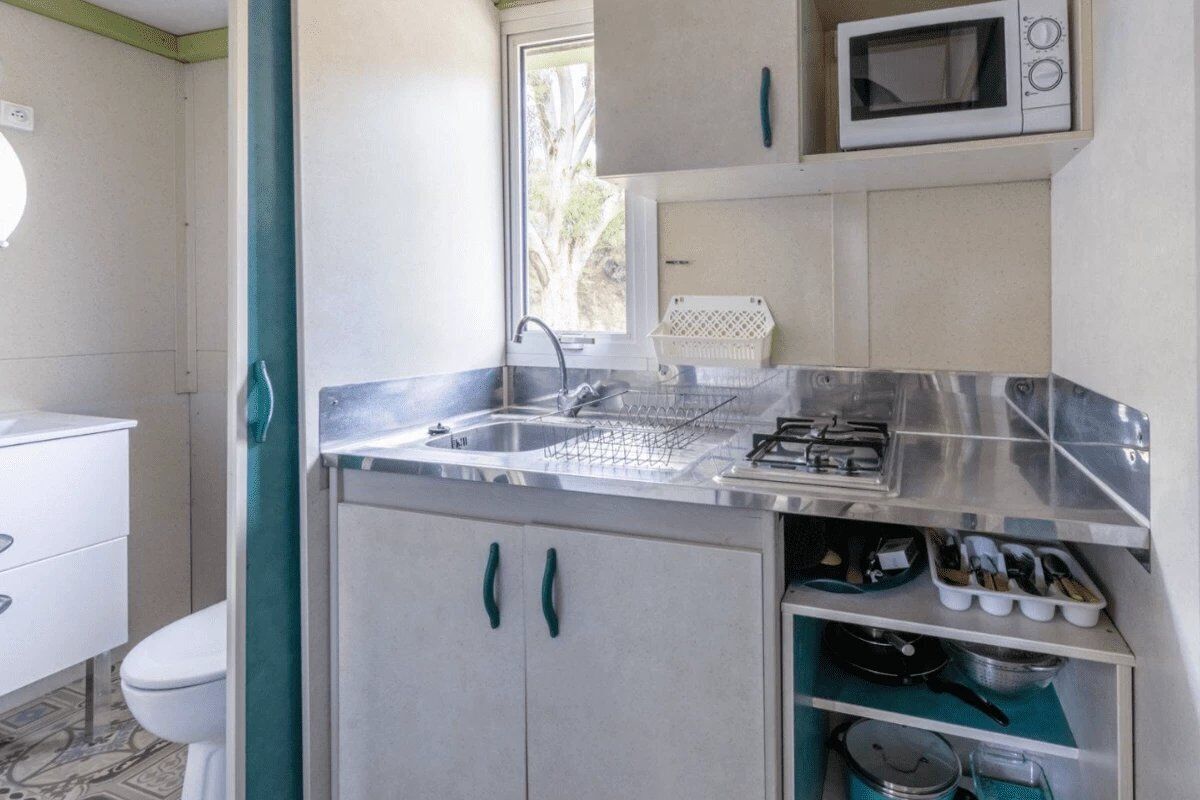 A compact kitchen with a sink, stove, and microwave.