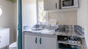 A compact kitchen with a sink, stove, and microwave.