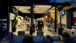 An outdoor dining area with tables and chairs, surrounded by potted plants.